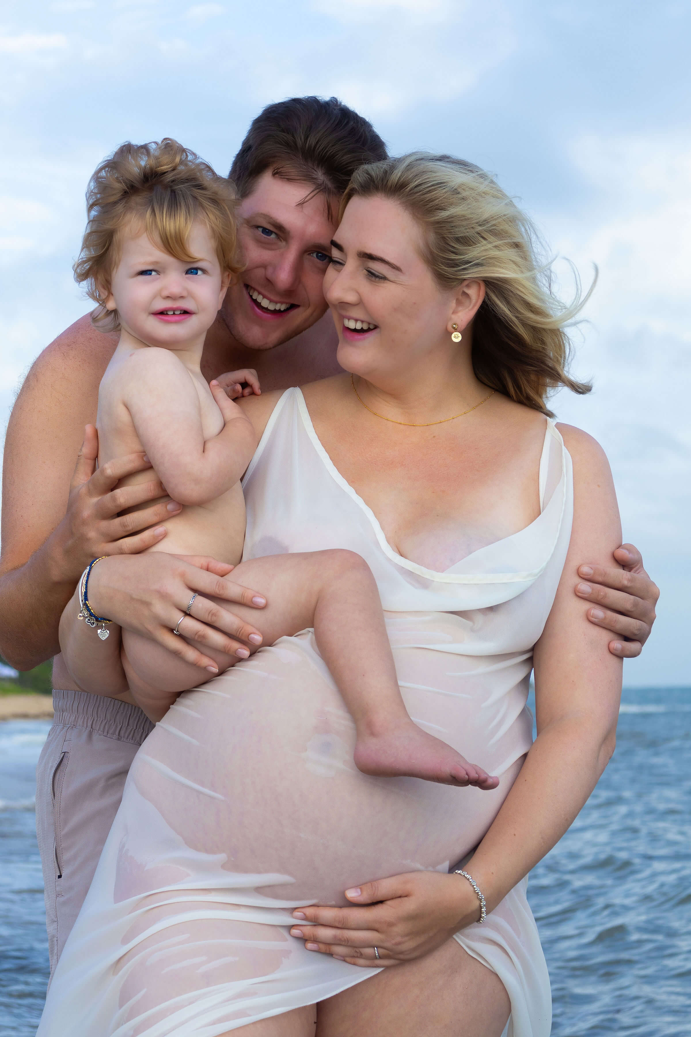 a loving family standing in front of the ocean