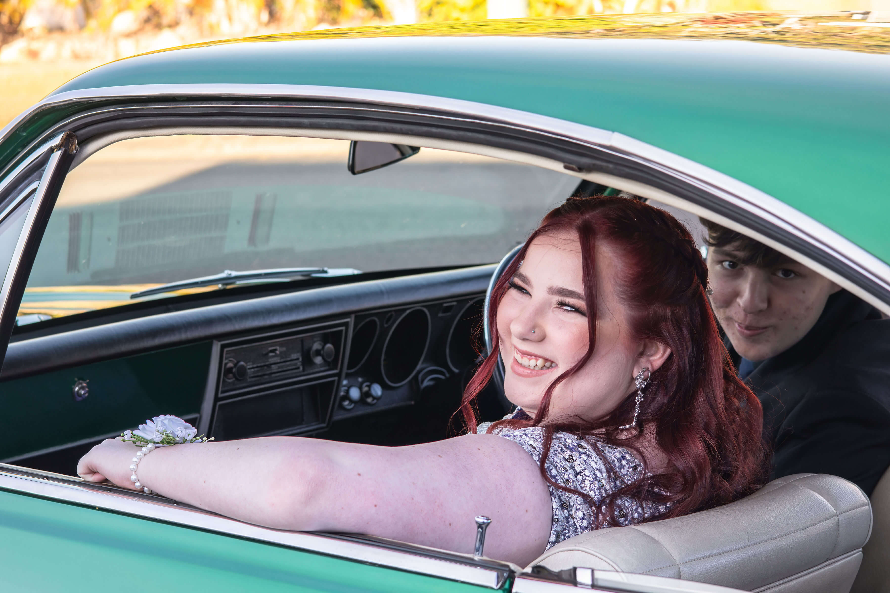 a couple sitting in a car looking at the camera smiling