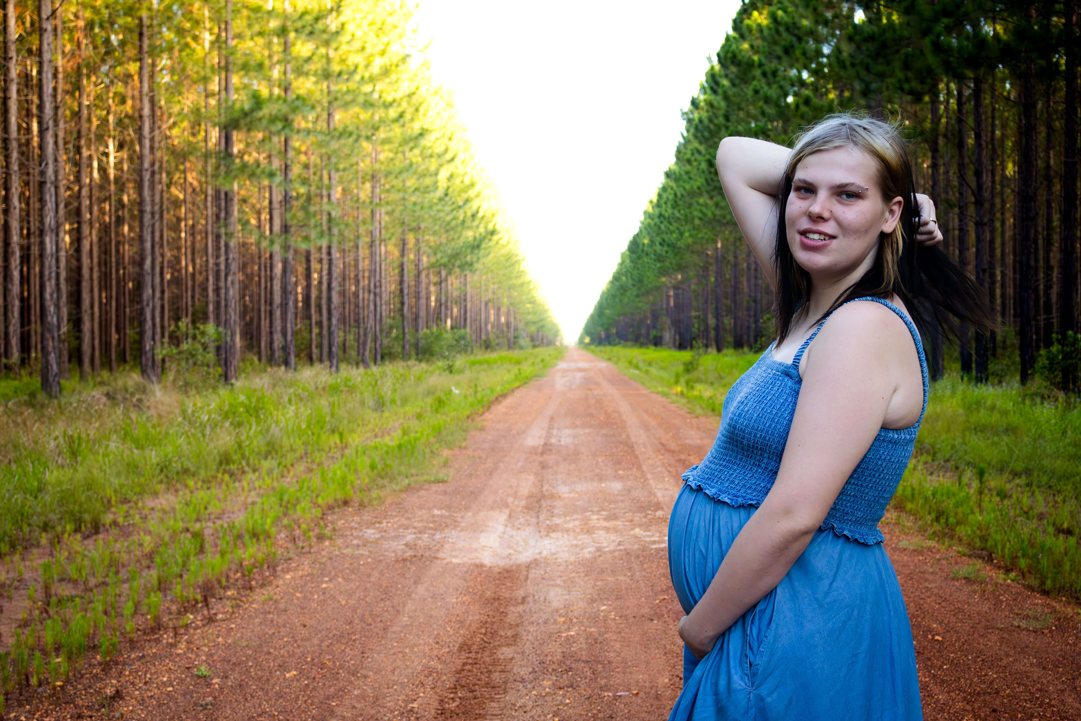 a women in a blue dress standing on a path in the forest